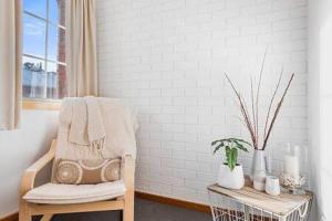 a room with a chair and a table with a plant at Cosy renovated 2 bed villa in superb location in Hobart