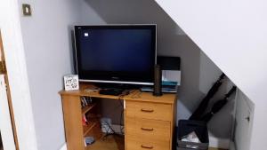 una televisione seduta su un supporto in legno in una stanza di Iris House a Belfast