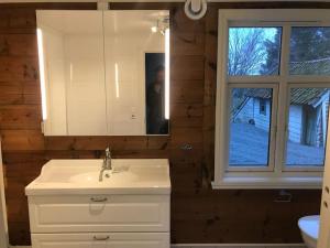 baño con lavabo, espejo y ventana en Koselig stort gårdshus, m/boblebad. Båt kan leies, en Forland