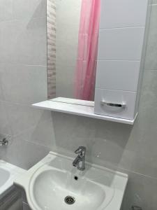 y baño con lavabo blanco y espejo. en ЖК Махаббат, en Aktau