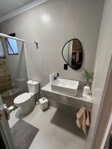 a bathroom with a sink and a toilet and a mirror at Apartamento duplo com banheiro privativo in São José