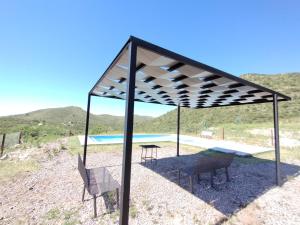 a pavilion with chairs and a table and a pool at Potrero del Rey in Estancia Grande