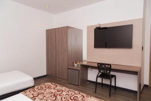 1 dormitorio con escritorio, TV y silla en Hotel Laureles Loft en Medellín