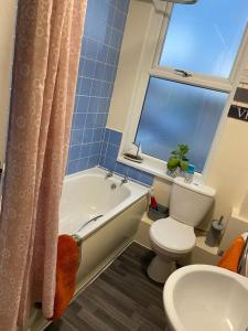 a bathroom with a toilet and a tub and a window at Comfortable 2beds house 4 contractors & staycation in Leeds