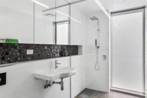 y baño blanco con lavabo y ducha. en New Architect designed Coastal retreat-water views en Hobart