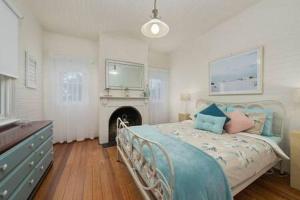 a bedroom with a bed with blue pillows and a fireplace at The Baker's Cottage in the Heart of Richmond Sleeps 6 in Hobart