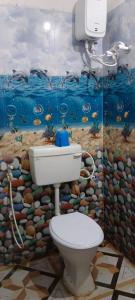 a bathroom with a toilet and a painting on the wall at Ocean front beach resort in Tajpur