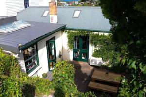 a white house with green doors and a bench at Bostane Cottage on West Hobart Hill in Hobart