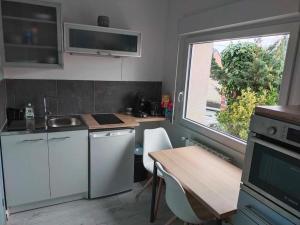 eine kleine Küche mit einem Tisch und einem Fenster in der Unterkunft La maison aux escargots *Jacuzzi* in Hénin-Beaumont