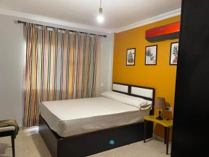 a bedroom with a bed and a yellow wall at Quiet and distinctive apartment with a wonderful v in Madinaty