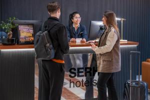 un hombre y una mujer de pie en un escritorio en SERHS Carlit Boutique Hotel, en Barcelona
