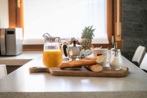 a table with a cutting board with bread and orange juice at Casa Mia ,APT WiFi e Parcheggio nel cuore del Friuli in Osoppo