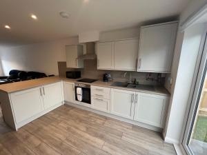a kitchen with white cabinets and a wooden floor at Inchmurrin Townhouse, Loch Lomond in Bonhill