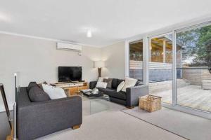 Hidden Bay Retreat-5 Bed- 15min to Hobart في هوبارت: غرفة معيشة بها كنبتين وتلفزيون