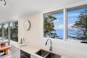 cocina con ventanas, fregadero y reloj en Hidden Bay Retreat-5 Bed- 15min to Hobart en Hobart