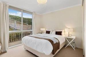 - une chambre avec un grand lit et une grande fenêtre dans l'établissement Hidden Bay Retreat-5 Bed- 15min to Hobart, à Hobart