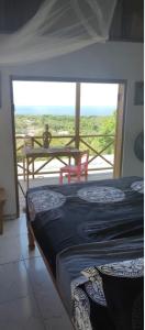 a bedroom with a bed and a balcony with a table at Backra`s Villa in Port Antonio