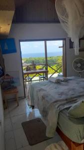 a bedroom with a bed and a balcony with a view at Backra`s Villa in Port Antonio