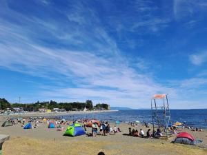 a group of people on a beach with a lifeguard tower at Cabaña a pasos de la Playa in Puerto Montt