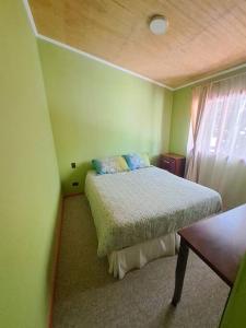 ein Schlafzimmer mit einem Bett in einem grünen Zimmer in der Unterkunft Cabaña a pasos de la Playa in Puerto Montt