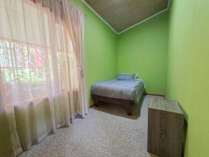 a green room with a bed and a window at Cabaña a pasos de la Playa in Puerto Montt