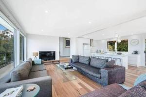 a living room with two couches and a kitchen at House on the Hill with a View-Sleeps 12 in Hobart