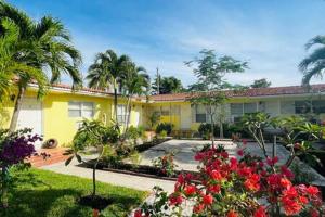 un edificio amarillo con palmeras y flores en un patio en Cozy xxl studio FREE Parking, en Miami