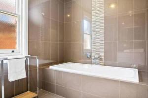 a bathroom with a bath tub and a window at Charming inner city home excellent base in Hobart in Hobart