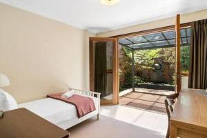 1 dormitorio con 1 cama y puerta que da a un patio en Charming inner city home excellent base in Hobart en Hobart