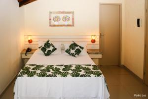 um quarto com uma cama branca e almofadas verdes em Hotel Rio Penedo em Penedo
