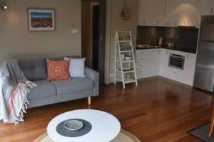 sala de estar con sofá y mesa en Modern 1 bed-walk Casino riverfront 5 mins to CBD en Hobart
