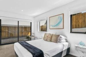 a white bedroom with a large bed and windows at Mountain View Villa-close to shops-10min to CBD in Bellerive