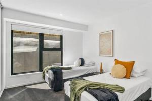 two beds in a room with a window at Mountain View Villa-close to shops-10min to CBD in Bellerive