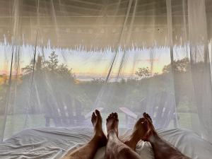 a person laying on a bed with their feet on a window at Wood cabin in the jungle with sea view in Puerto Jiménez