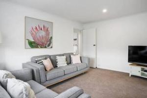 a living room with a couch and a flat screen tv at Sandy Bay Cozy Cottage Close to CBD in Hobart