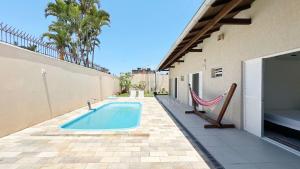 einen Pool mit Hängematte an der Seite eines Gebäudes in der Unterkunft Casa Mar & Brisa - Wi-fi e piscina in Guaratuba