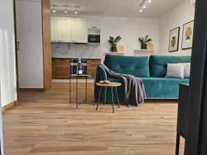 a living room with a blue couch and a kitchen at URBAN APARTMENTS PREMIUM, Opolska 10 No 67A, Free Garage, Self Check-in in Katowice