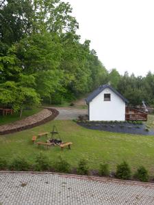 a yard with a white building and a picnic table at Leśny Zakątek- Domek Lipa in Parchowo
