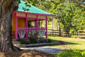 a pink building with a green roof next to a tree at Strawberry Fields Together in Robins Bay