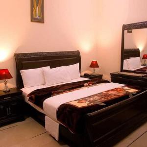 Un dormitorio con una cama grande y dos mesas con lámparas. en Hotel Moon Light view, en Lahore