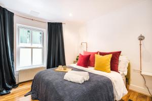UNIQE 2 Bedroom PRIME LOCATION في لندن: غرفة نوم مع سرير كبير مع وسائد ملونة