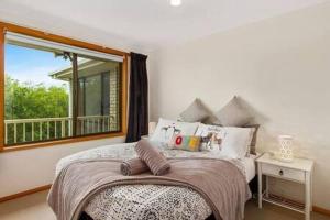 een slaapkamer met een bed met een spiegel en een raam bij Spacious Modern Home Outstanding Views sleeps 9 in Hobart