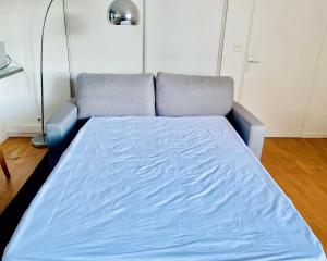 - un canapé bleu dans une chambre avec un lit dans l'établissement Comfortable 50 m apartment with parking, à Courbevoie