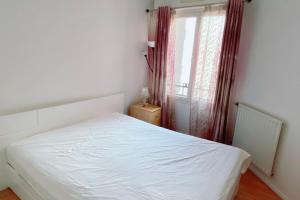 a white bed in a room with a window at Comfortable 50 m apartment with parking in Courbevoie