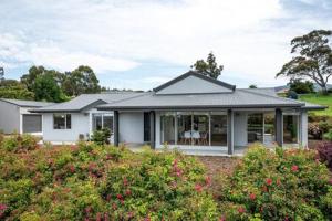 una casa blanca con un patio con arbustos y flores en The Rest Retreat Getaway 15 Mins to CBD 3 Bed en Hobart