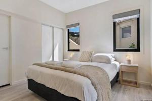 サンディ・ベイにあるThe View Studio Apartment Fully self-contained Sandy Bayの白いベッドルーム(ベッド2台、窓付)