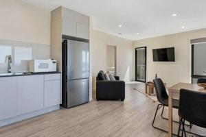 サンディ・ベイにあるThe View Studio Apartment Fully self-contained Sandy Bayのテーブルと冷蔵庫のあるキッチンとリビングルーム