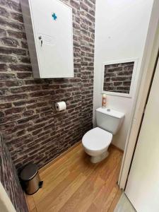 a bathroom with a white toilet and a brick wall at Ulis très beau 2 pièces tout équipé in Les Ulis +7 photos
