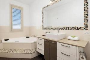 ein Badezimmer mit einem Waschbecken, einer Badewanne und einem Spiegel in der Unterkunft The View Sandy Bay 5 bedroom in Hobart