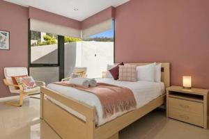 ein Schlafzimmer mit einem großen Bett und einem großen Fenster in der Unterkunft The View Sandy Bay 5 bedroom in Hobart
